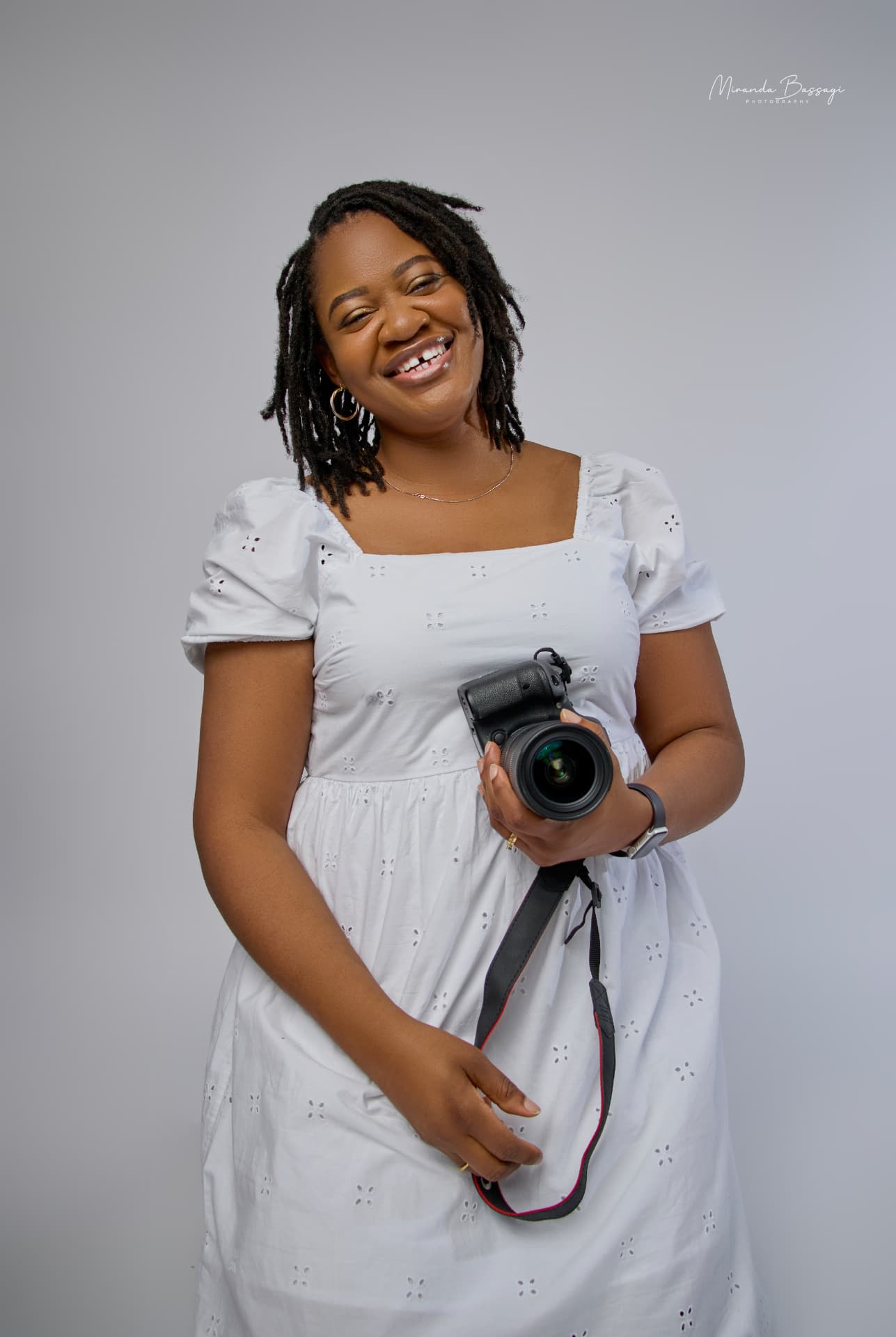 Professional portrait of Miranda smiling and holding a camera